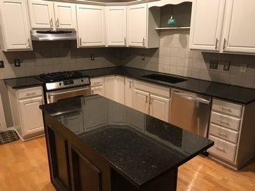 A kitchen with black granite counter tops and white cabinets