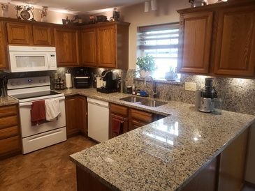 A kitchen with granite counter tops and wooden cabinets.