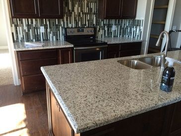 A kitchen with granite counter tops , a stove and a sink.