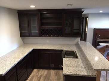 A kitchen with granite counter tops and dark cabinets
