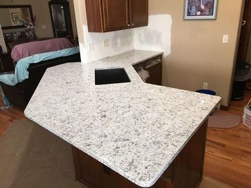 A kitchen with a white granite counter top and a sink.