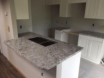 A kitchen with granite counter tops and white cabinets.