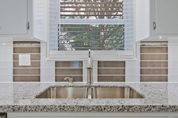 A kitchen with a sink and a window with blinds.