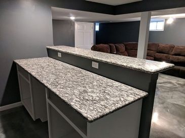A kitchen with granite counter tops and a couch in the background.