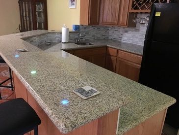 A kitchen with a granite counter top and a black refrigerator.