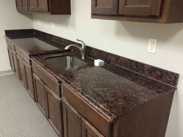A kitchen with a sink , cabinets and granite counter tops.