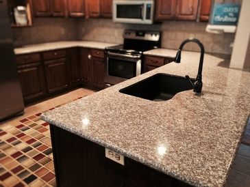 A kitchen with granite counter tops and a black sink