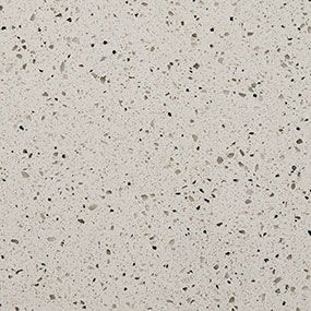 A close up of a white granite counter top with black spots.