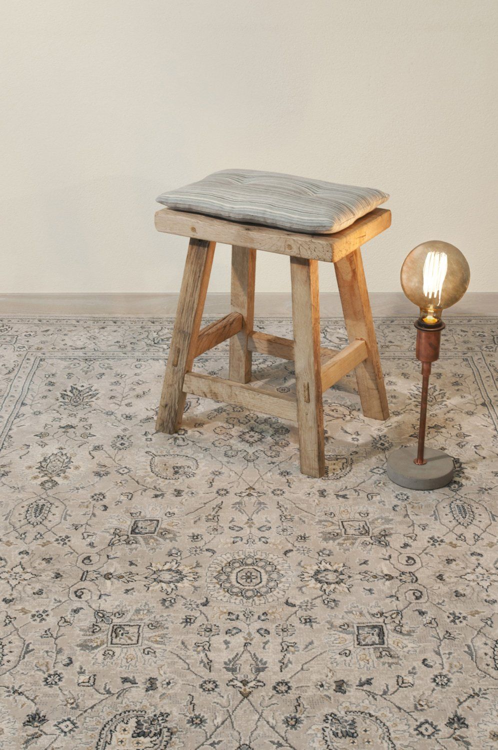 Traditional rug beneath modern light fixture and stool