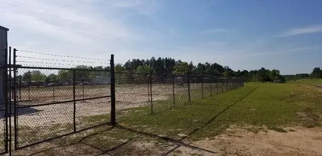 A barbed wire fence surrounds a large grassy field.