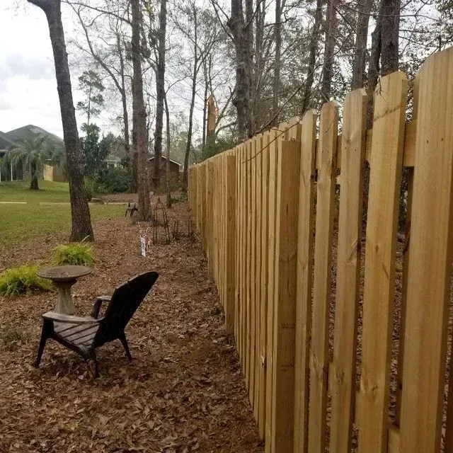 A wooden chair sits next to a wooden fence