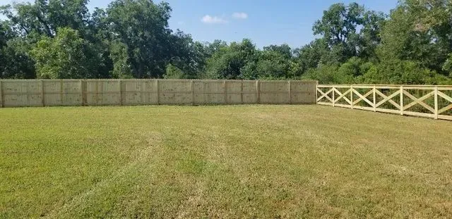 There is a wooden fence in the middle of a grassy field.