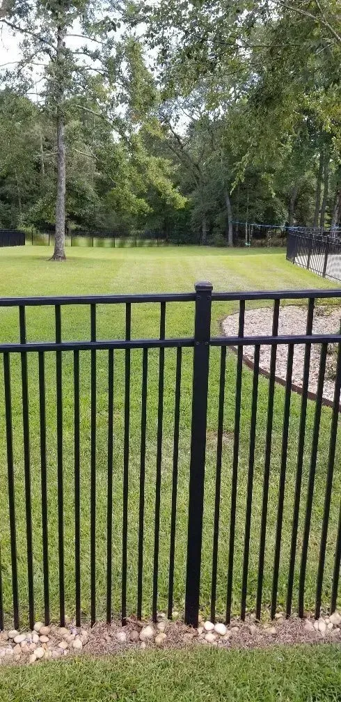 A black fence surrounds a lush green field.