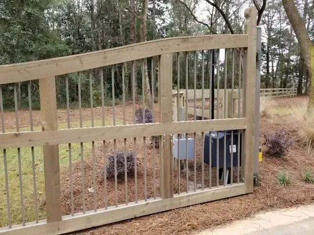 A wooden gate with metal bars is sitting on the side of a road.