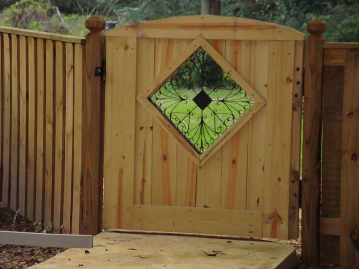 A wooden gate with a square window in the middle