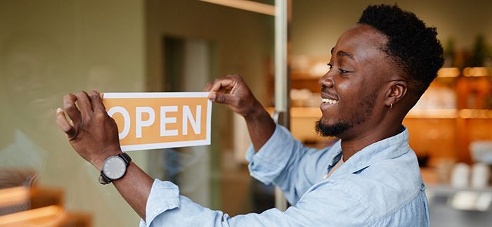 A man is holding a sign that says `` open '' on a glass door.