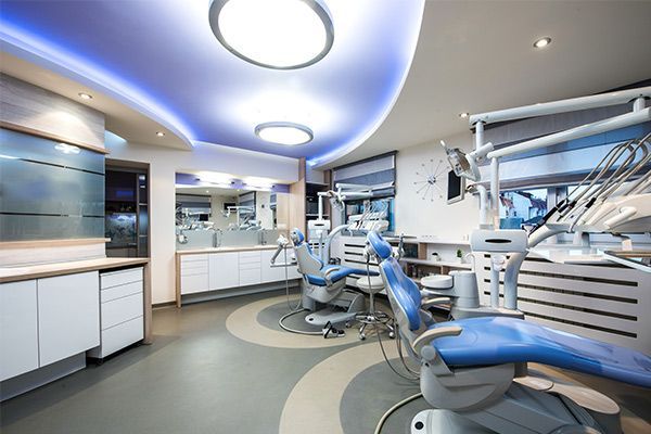 A dental office with blue chairs and a blue ceiling.