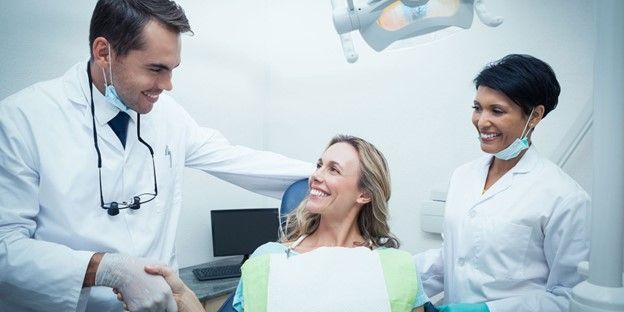 dentist smiling with staff behind her | selling dental practice
