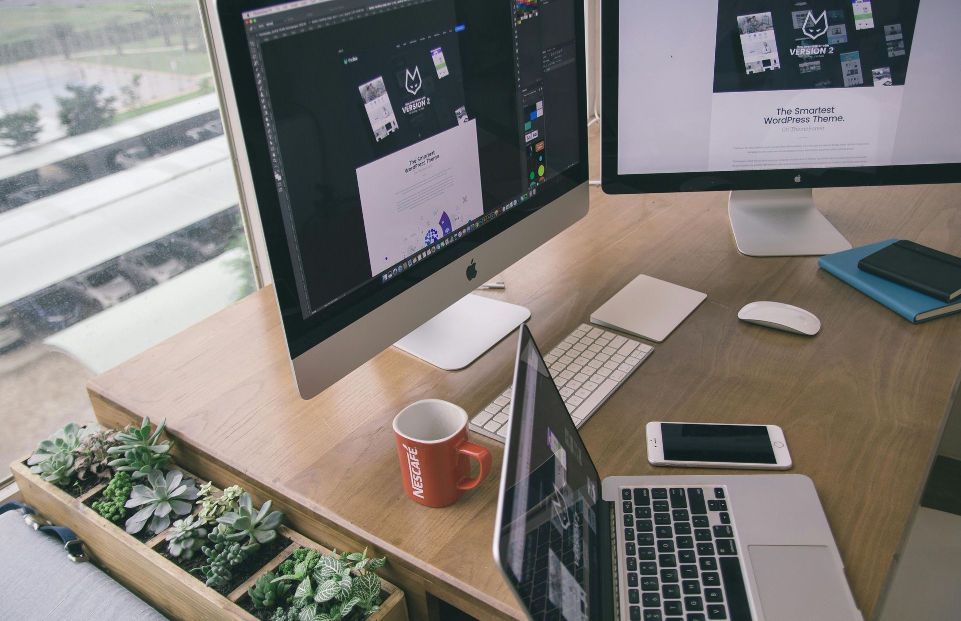 A desk with two computer monitors and a laptop on it