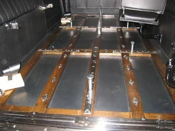Inside a hearse: Wooden slats over metal panels, with a jump seat at the right.