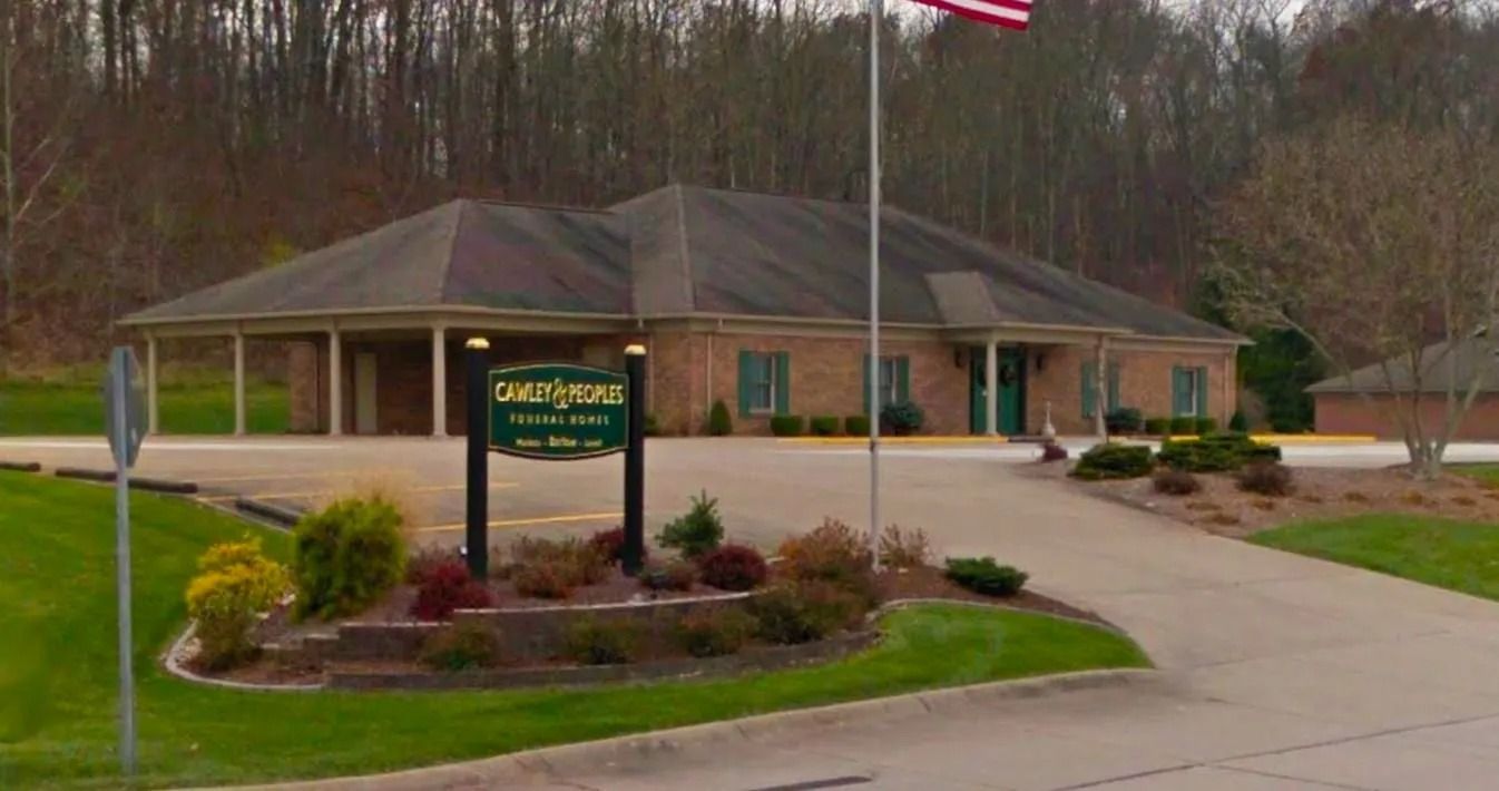 Oak Grove funeral home building with green lawn, driveway, and sign, American flag on pole.