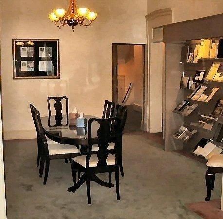 Dining room with oval table, six chairs, framed pictures, display shelves, and a chandelier.