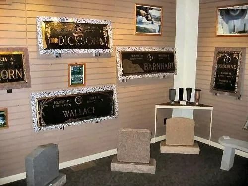Display of memorial plaques and headstones in a showroom, featuring names like Dickson, Barnhart, and Wallace.
