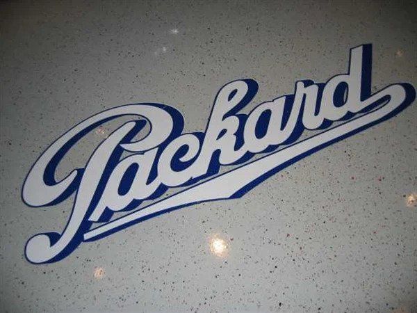 White and blue Packard logo on a speckled gray background.
