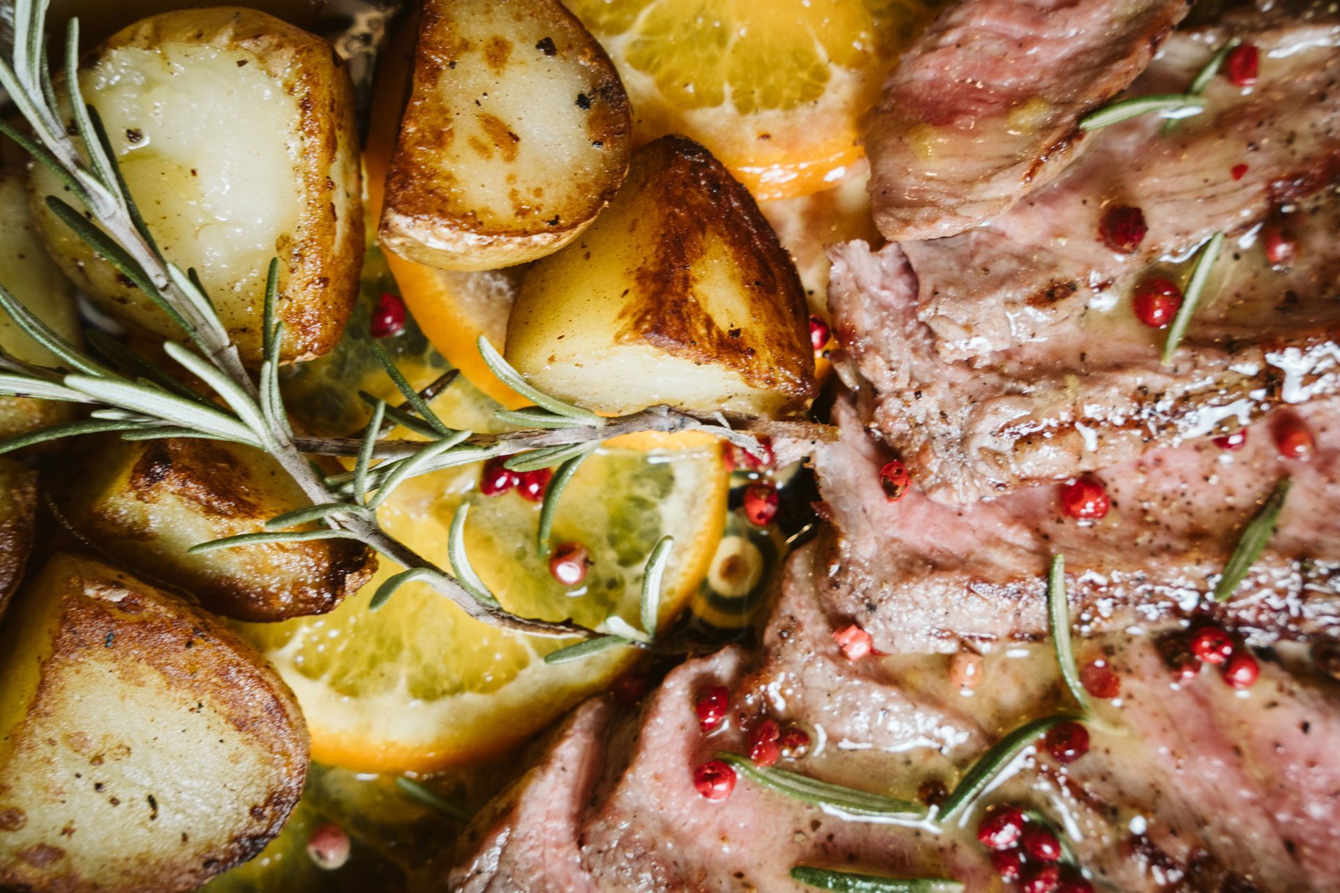 Patate arrosto, fette d'arancia e carne affettata condita con erbe aromatiche e grani di pepe.