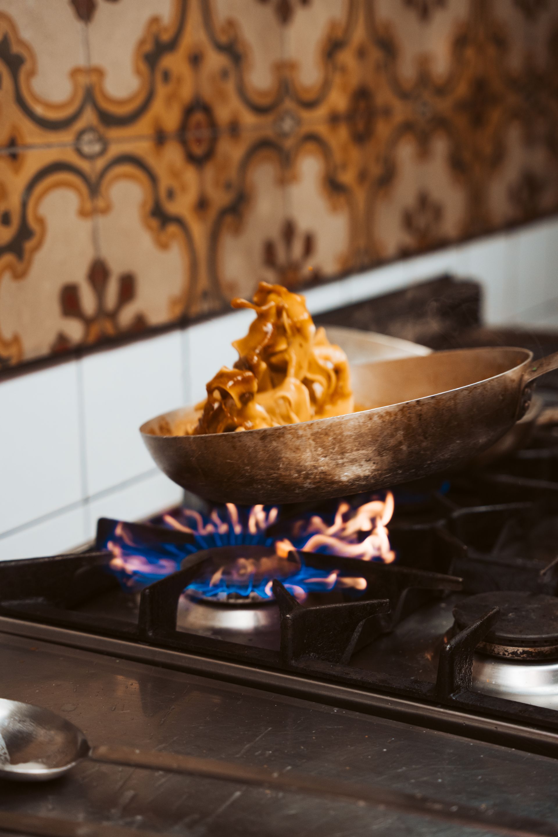 Cibo dorato cotto in una padella su una fiamma blu su un fornello, in cucina.