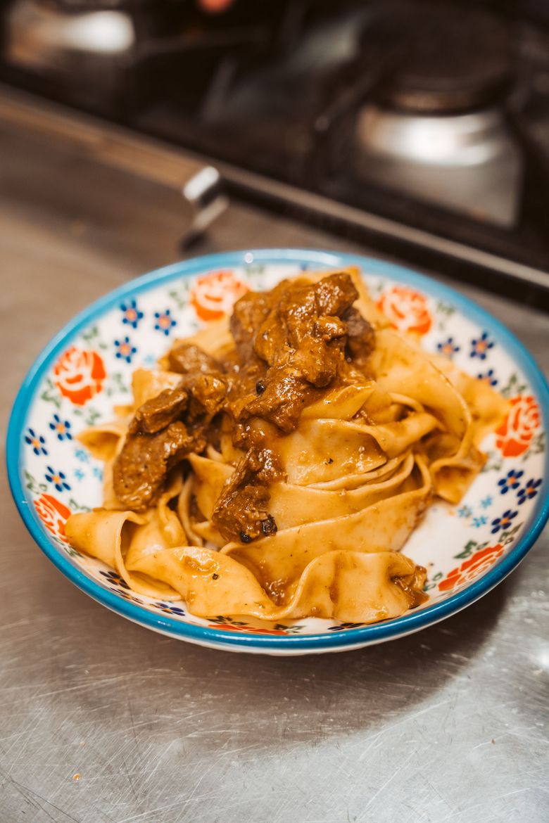 Pasta al ragù in una ciotola decorativa, su una superficie metallica vicino ai fornelli.