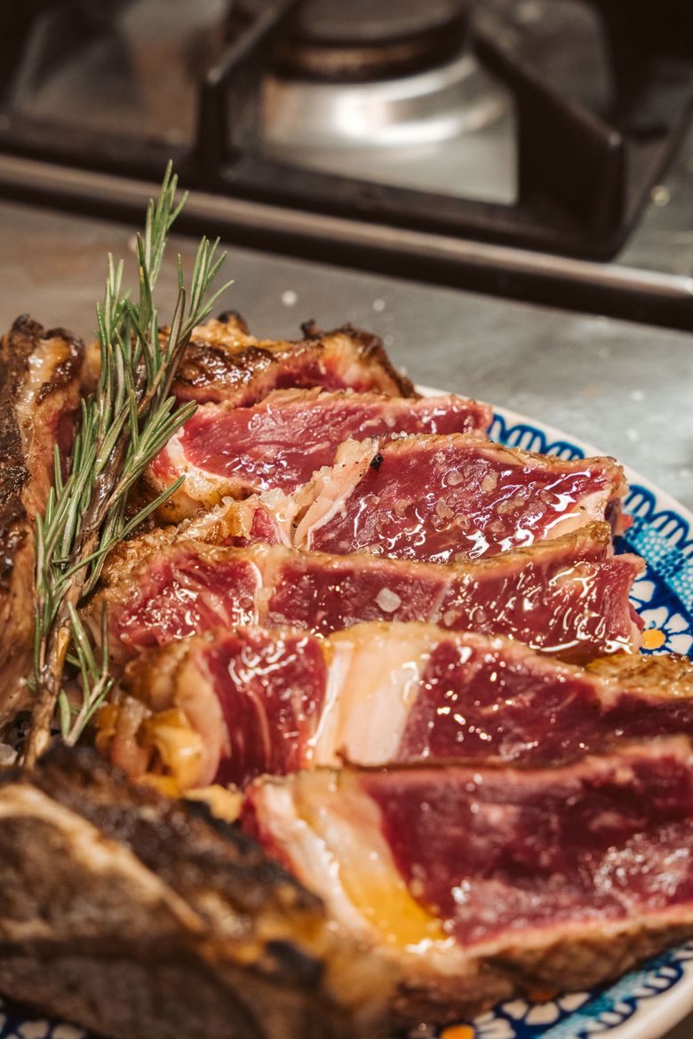 Bistecca tagliata a fette e cotta su un piatto decorativo, guarnita con rosmarino.