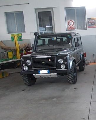 Land Rover Defender nero parcheggiato in un garage. Ha pneumatici di grandi dimensioni, uno snorkel e un paraurti anteriore.