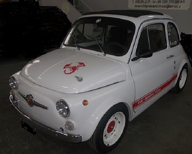 Fiat 500 Abarth bianca, auto d'epoca, striscia laterale rossa e stemma sul cofano, cerchi bianchi.