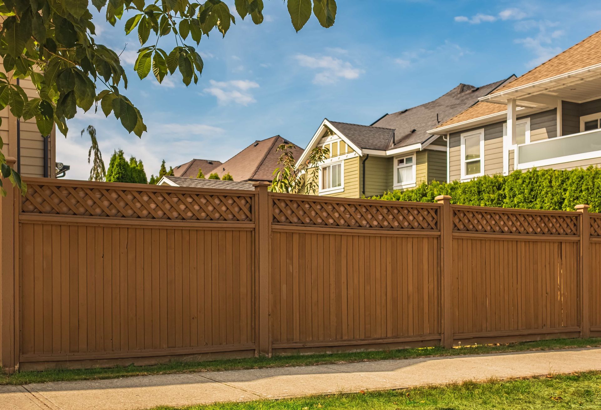 A wooden fence surrounds a residential area with houses in the background.