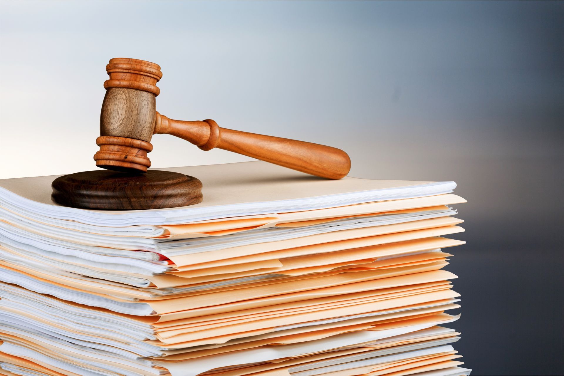 A wooden judge 's gavel is sitting on top of a stack of papers.