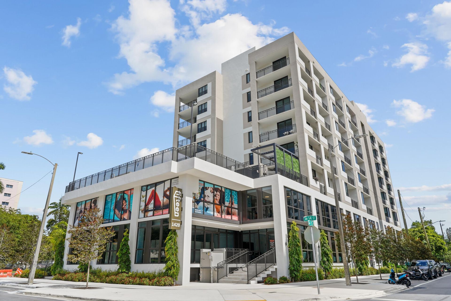Exterior view of a modern multi-story apartment building with ground-floor retail storefronts.