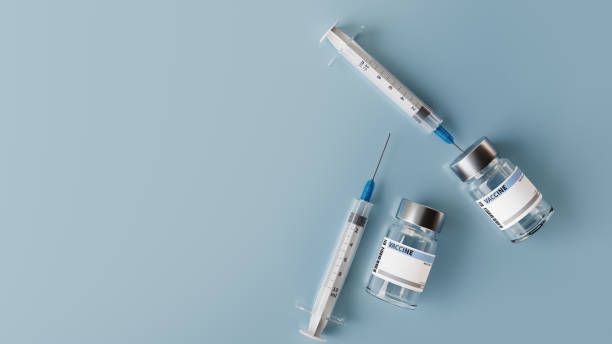 A syringe and two bottles of vaccine on a blue background.