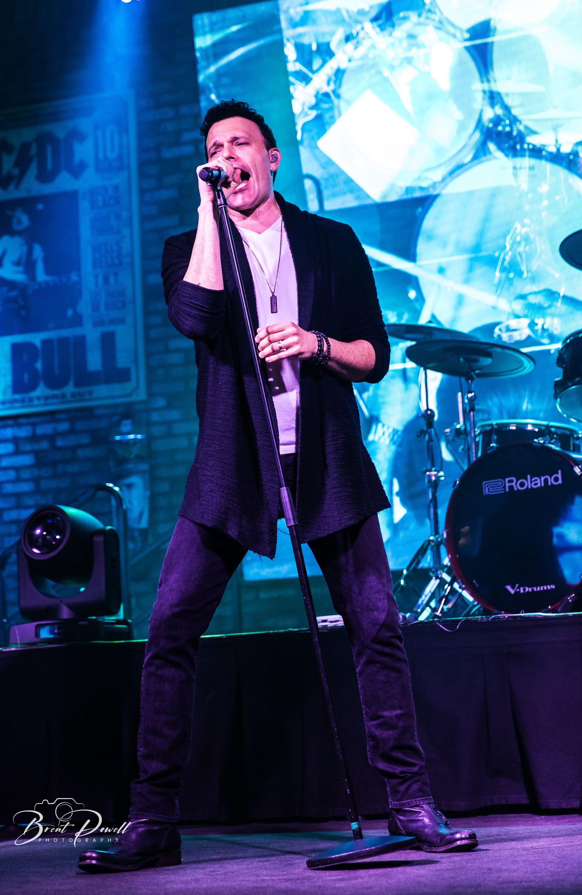 A man singing into a microphone in front of a sign that says bull