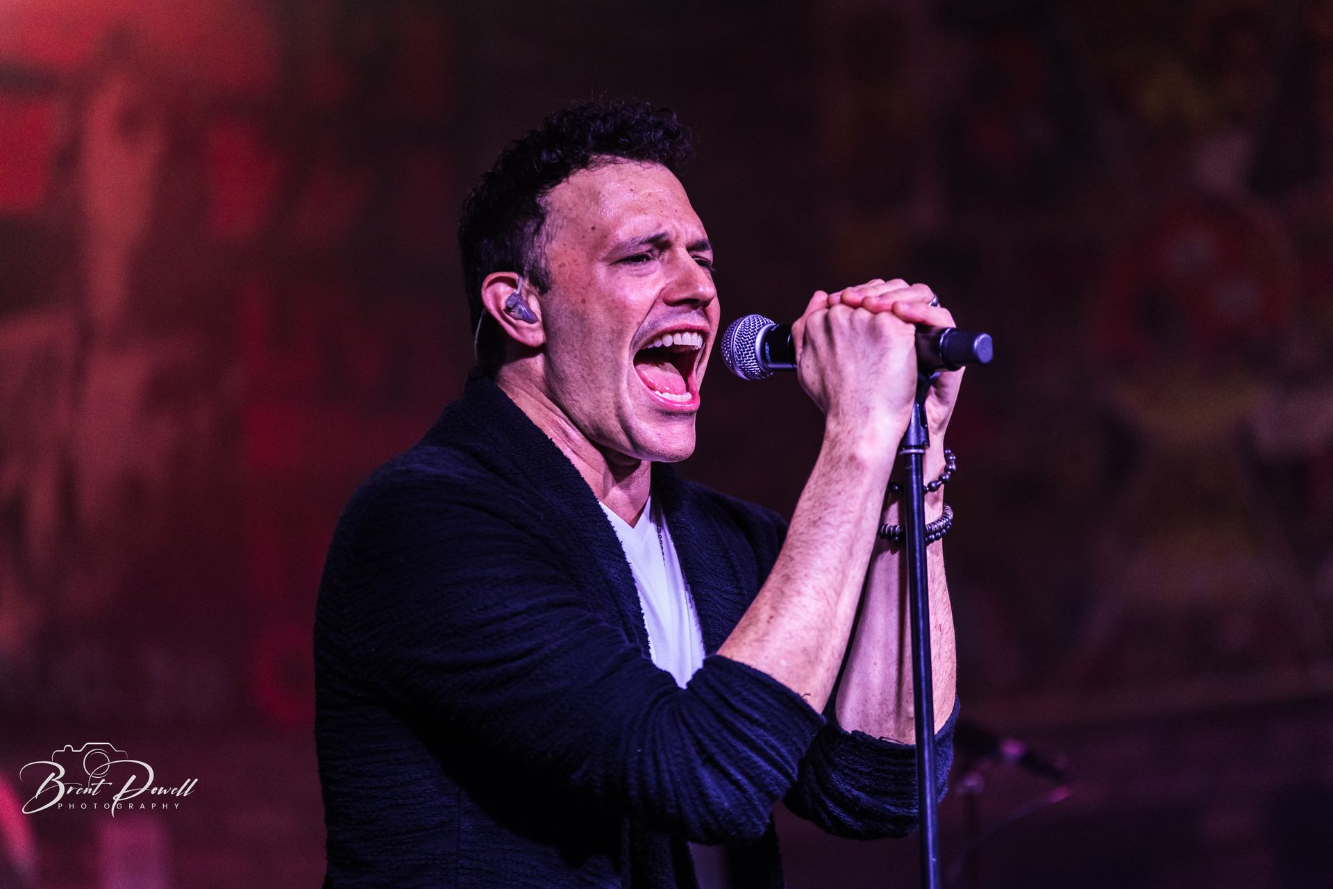 A man is singing into a microphone on a stage.