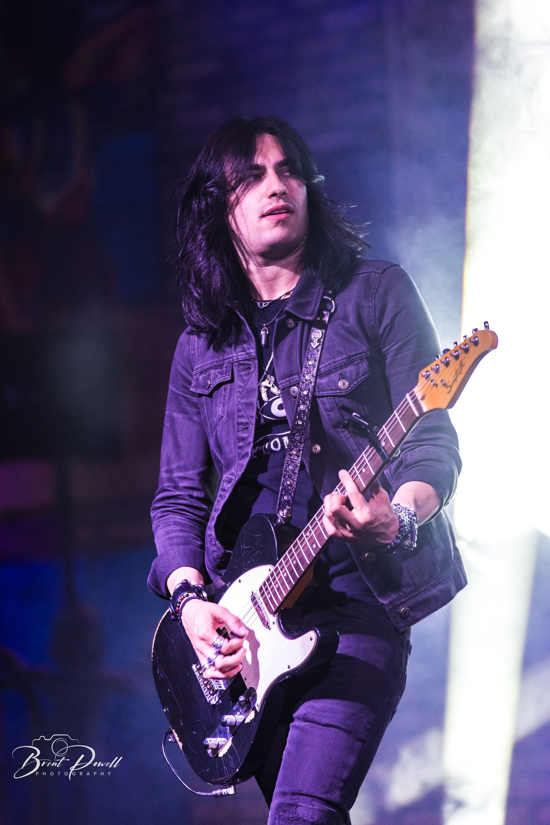 A man with long hair is playing a guitar on a stage.
