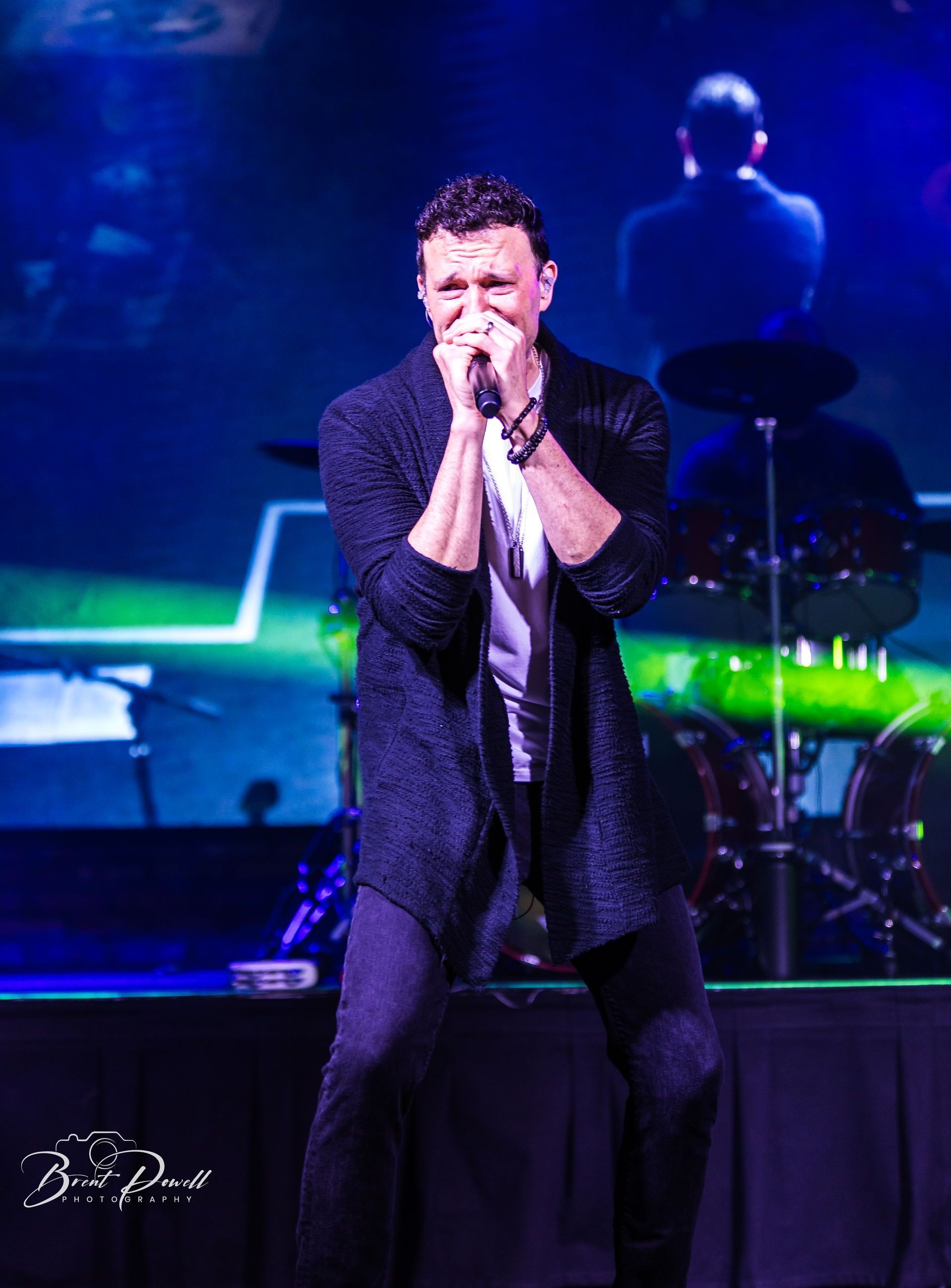 A man is singing into a microphone on a stage.