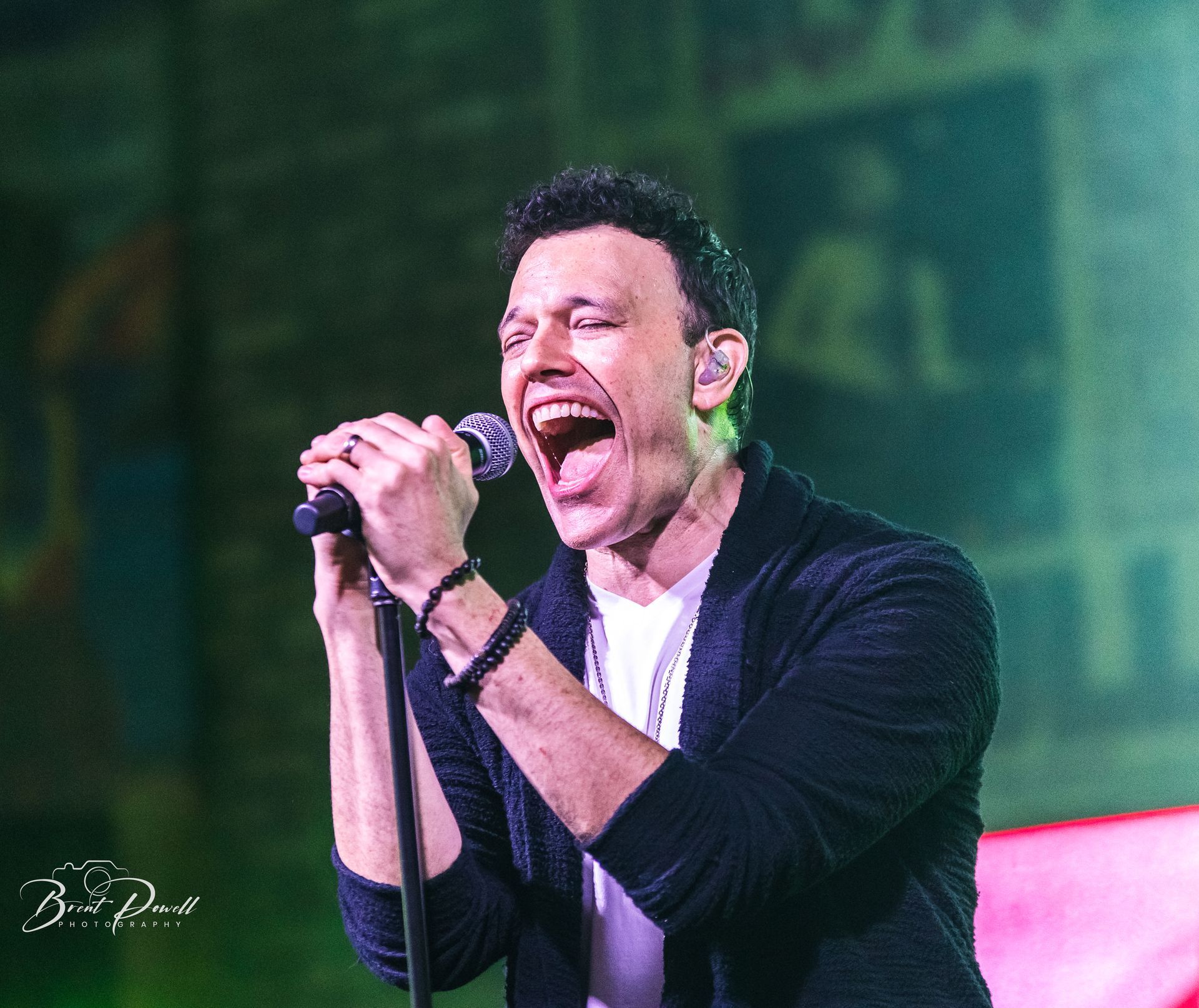 A man is singing into a microphone with his mouth open.