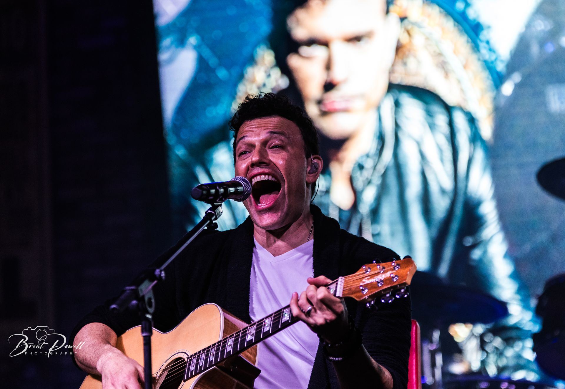 A man is singing into a microphone while playing a guitar.