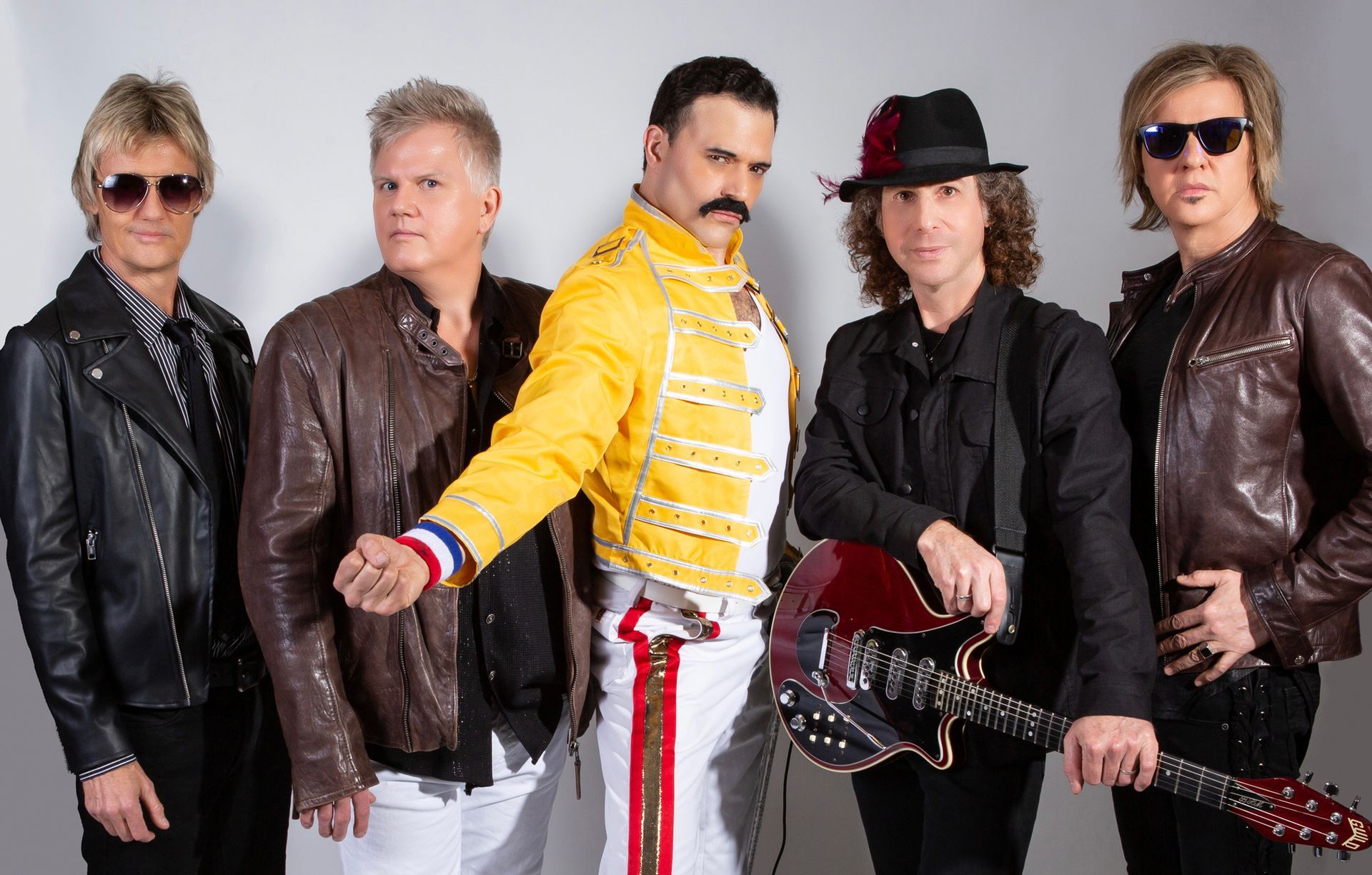A group of men standing next to each other with one man holding a guitar.