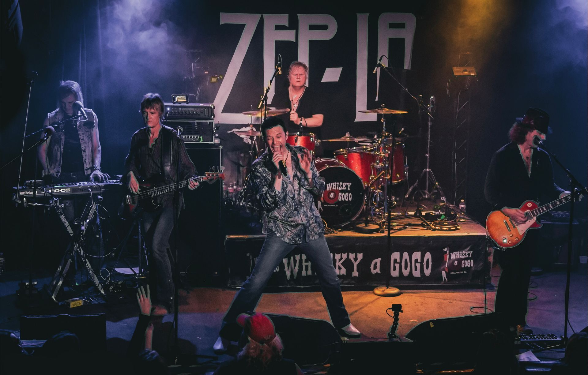 A group of people are playing instruments on a stage in front of a sign that says zfp-jr