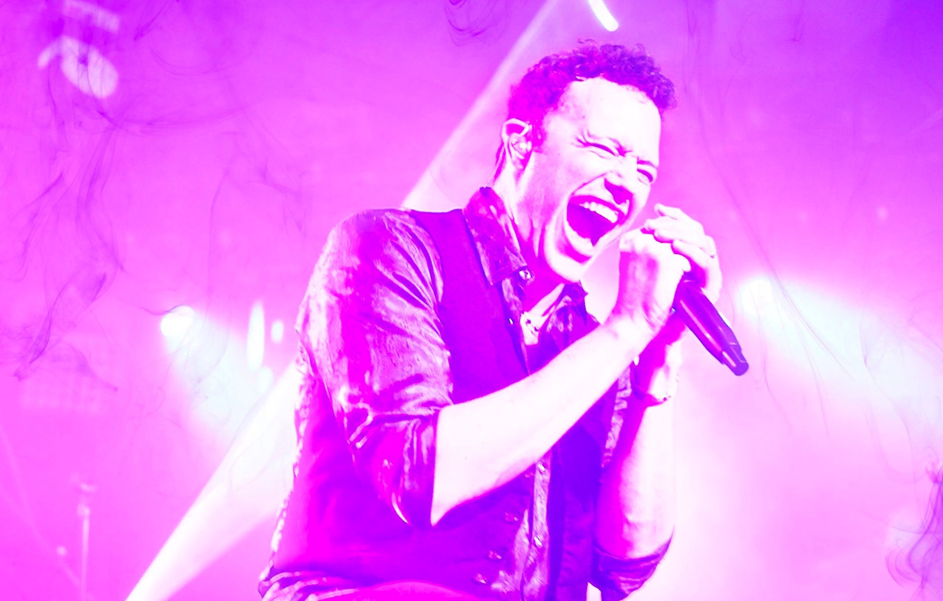 A man is singing into a microphone on a stage.