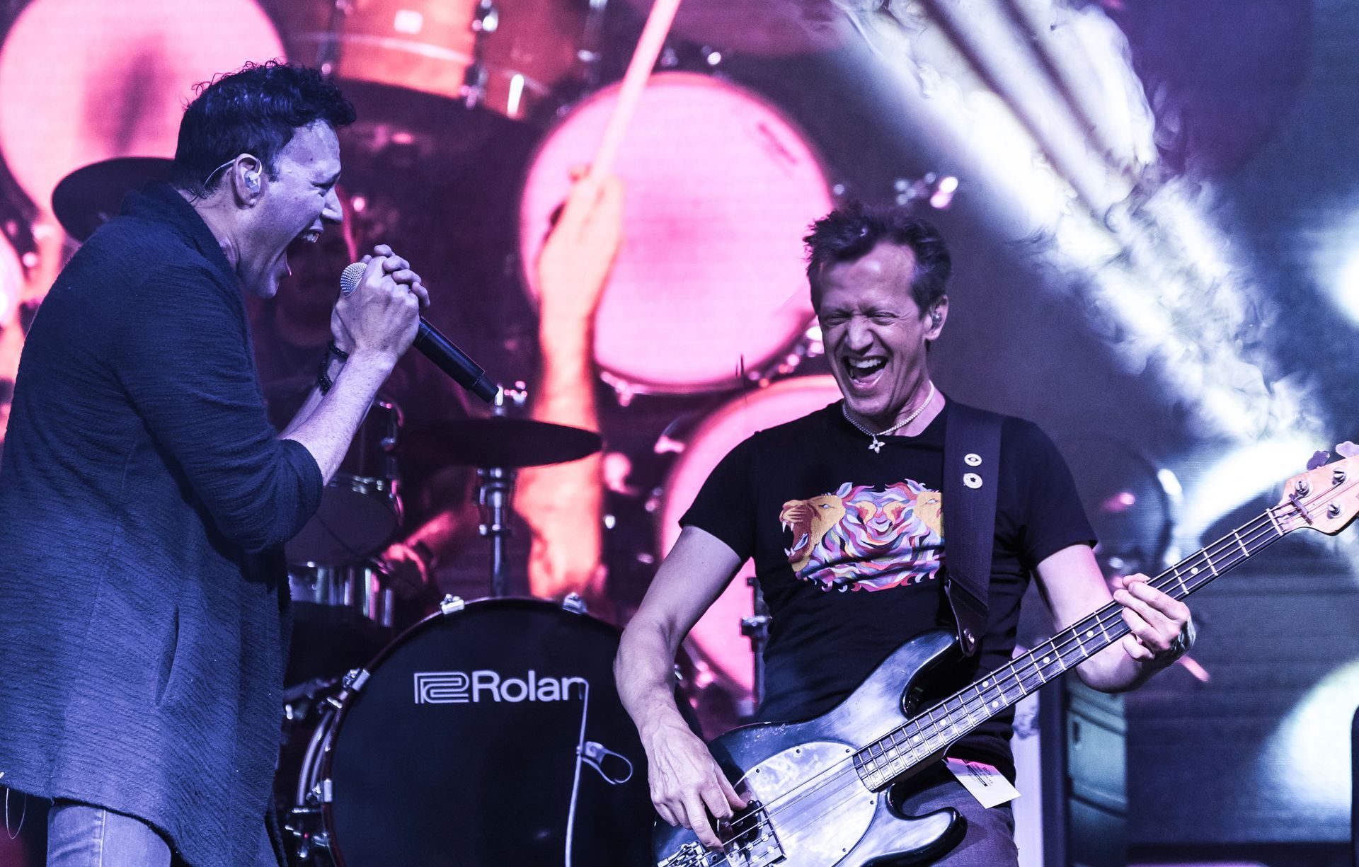 A man singing into a microphone while another man plays a guitar