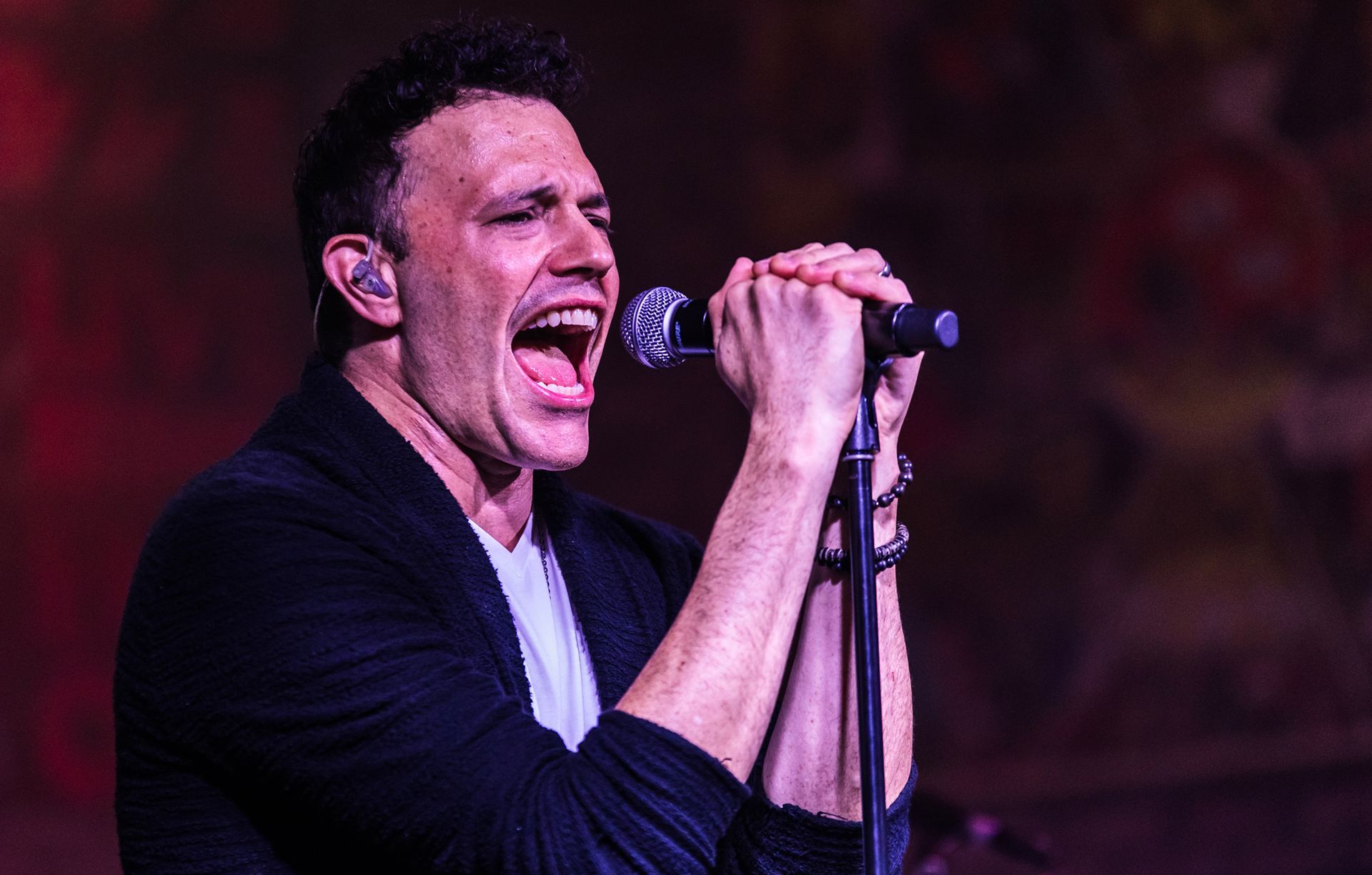 A man is singing into a microphone on a stage.