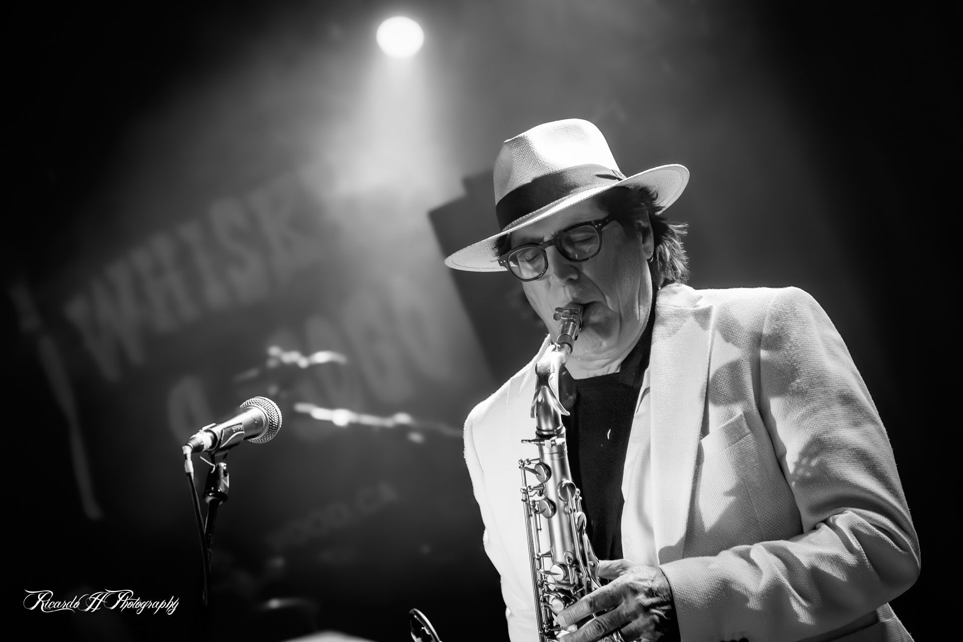 A man in a hat is playing a saxophone on a stage.